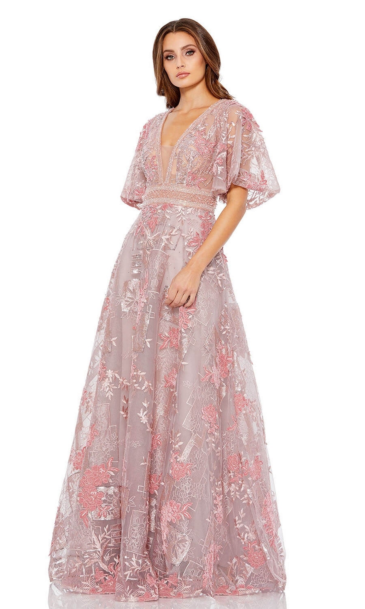 A woman models the Long Formal Dress 20262 by Mac Duggal, an A-line embroidered gown in sheer pink with a deep V-neckline, floral accents, and flounce sleeves, standing against a white background.